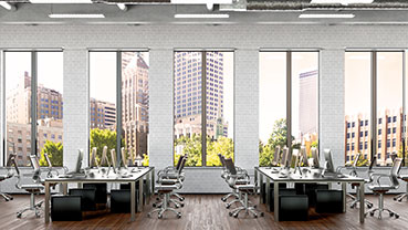 Open office lined with desks and computers overlooking a city skyline.