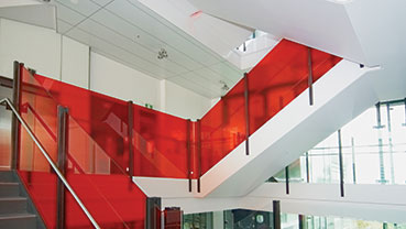 Interior staircase with bright red glass panel railings.