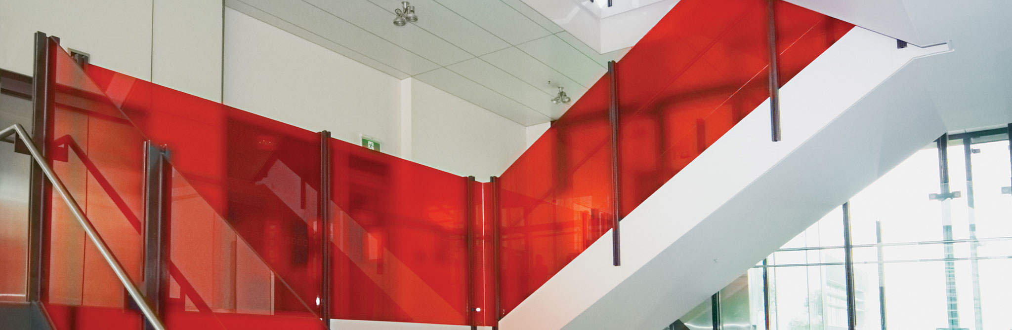 Interior staircase with bright red glass panel railings. 